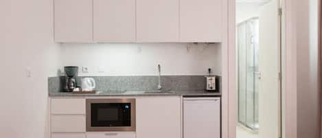 A modern kitchen with a microwave, toaster, and coffee maker. There is a small dining table with two chairs.