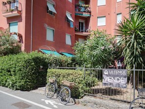 Un bâtiment rouge doté de balcons, un vélo et une pancarte indiquant une vente immobilière.