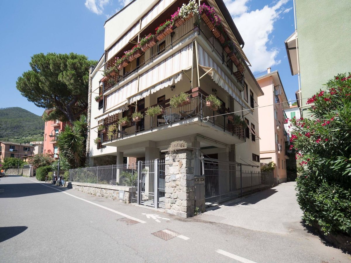 A multi-story building with balconies, a stone base, and a street view.