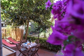 Une terrasse extérieure avec une table dressée pour le repas, entourée de chaises, et un toboggan rouge.