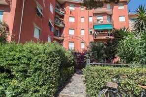 Un immeuble à plusieurs étages doté de balcons, d’un chemin pavé de pierres et de verdure.