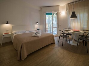 Une chambre d’hôtel comprenant un lit, des tables de chevet, un bureau avec des chaises et une fenêtre avec des rideaux.