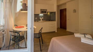 Une chambre d’hôtel comprenant un lit, un coin repas avec une table et des chaises, une kitchenette et une armoire.