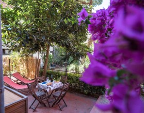 An outdoor patio with a table and chairs, surrounded by greenery and a fence. - Il Giardino di Ada Ground Floor Studio with AC and Patio (Monterosso al Mare)