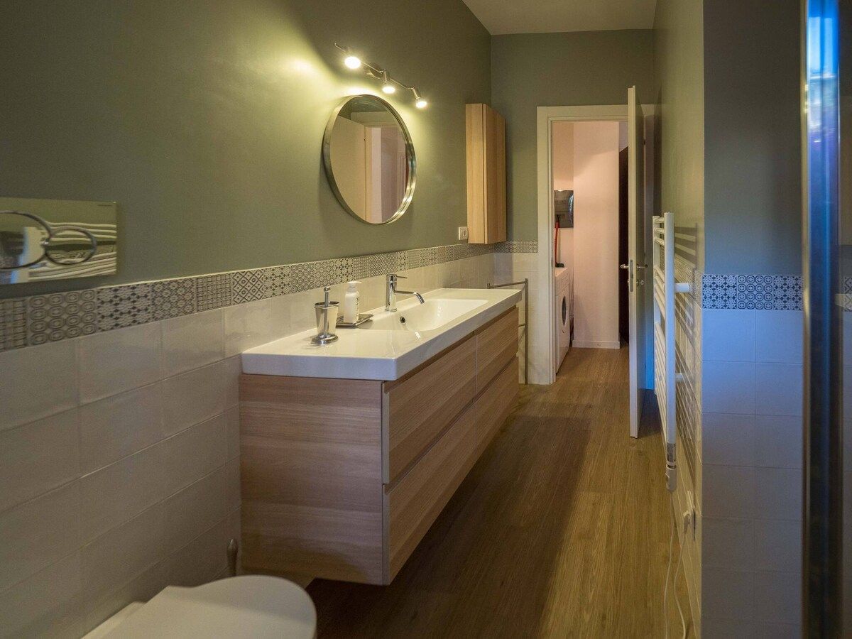 Ein modernes Badezimmer mit einem großen Spiegel, einem Waschbecken und einer Toilette.