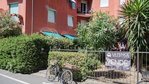 A red building with balconies, a bicycle, and a sign for 'LA FENICE IMMOBILIARE VENTE'. - Scimiscià 2 bedroom Apartment (Monterosso al Mare)