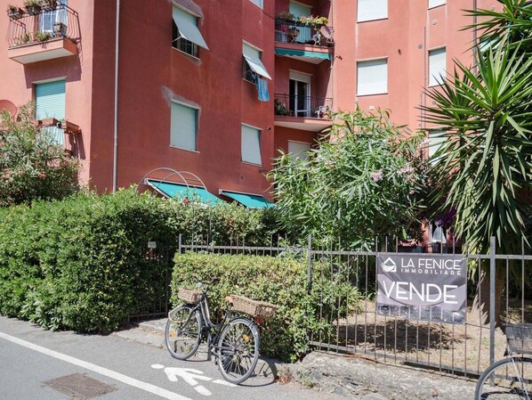Un bâtiment rouge doté de balcons, un vélo et une pancarte indiquant une vente immobilière.