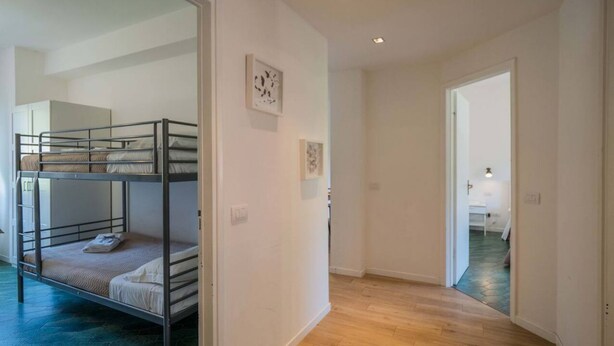 A room with bunk beds, a hallway with wooden flooring, and a door leading to another room. - Scimiscià 2 bedroom Apartment (Monterosso al Mare)