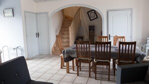 A dining area with a wooden staircase, a table with chairs, and a sofa.