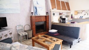 A living room with a fireplace, sofa, coffee table, and a TV.