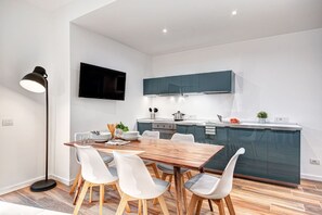Eine moderne Küche mit dunklen Schränken, einem Holztisch und weißen Stühlen.