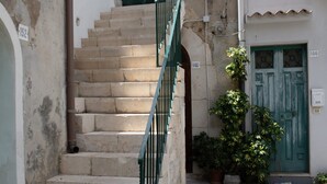 Una escalera estrecha con una puerta verde al final, que lleva a un edificio con puertas numeradas.