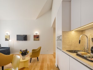Eine moderne Küche mit Spüle, Herd und Arbeitsplatte. Es gibt einen Essbereich mit Tisch und Stühlen.
