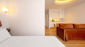 Een moderne hotelkamer met een bed, een slaapbank, een klein keukenhoekje en een bijzondere lamp.