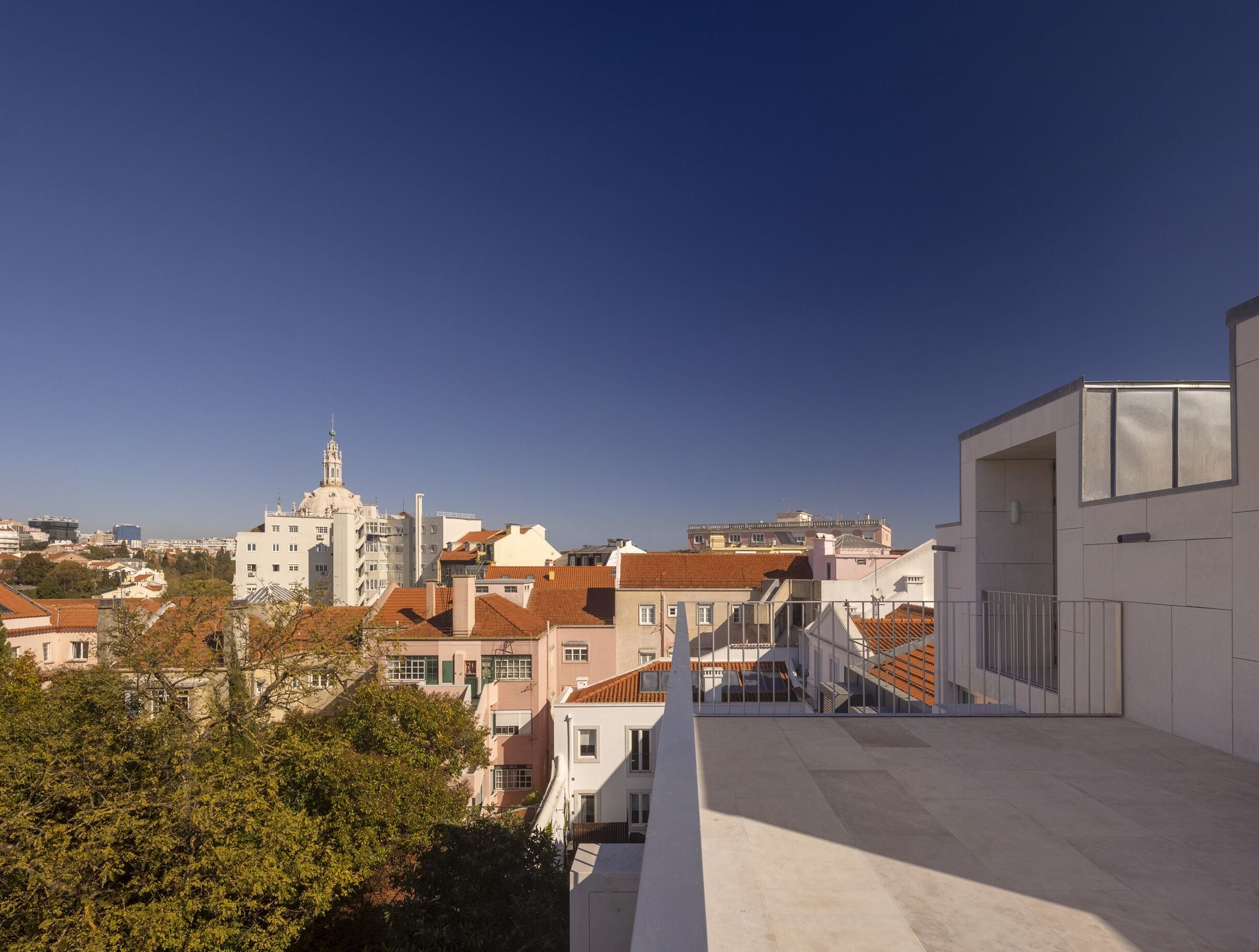 Un paisaje urbano con una mezcla de edificios modernos y tradicionales, una imponente aguja de iglesia y un cielo azul despejado.