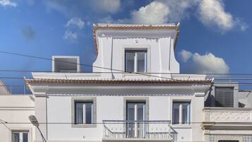 Un immeuble à plusieurs étages doté d’un balcon, de fenêtres et d’un toit recouvert de tuiles.