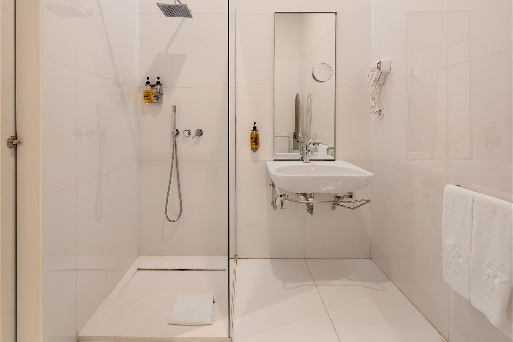 A modern bathroom with a shower, sink, and a towel rack.