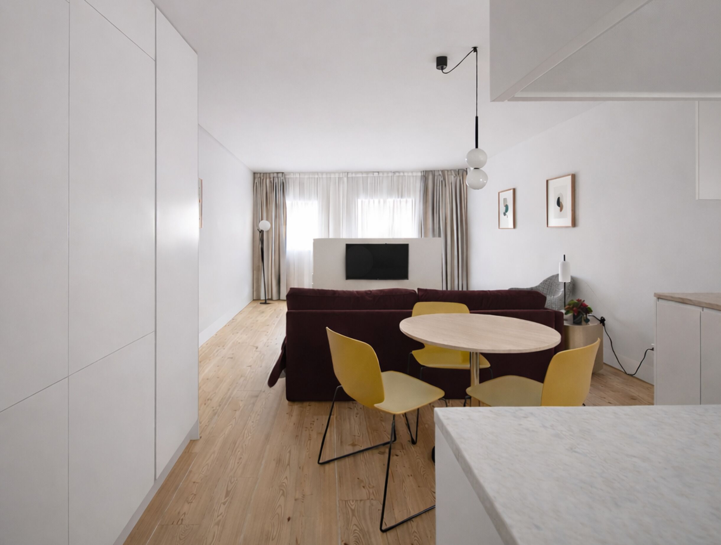 Ein modernes Wohnzimmer mit einer Couch, einem runden Tisch und gelben Stühlen.