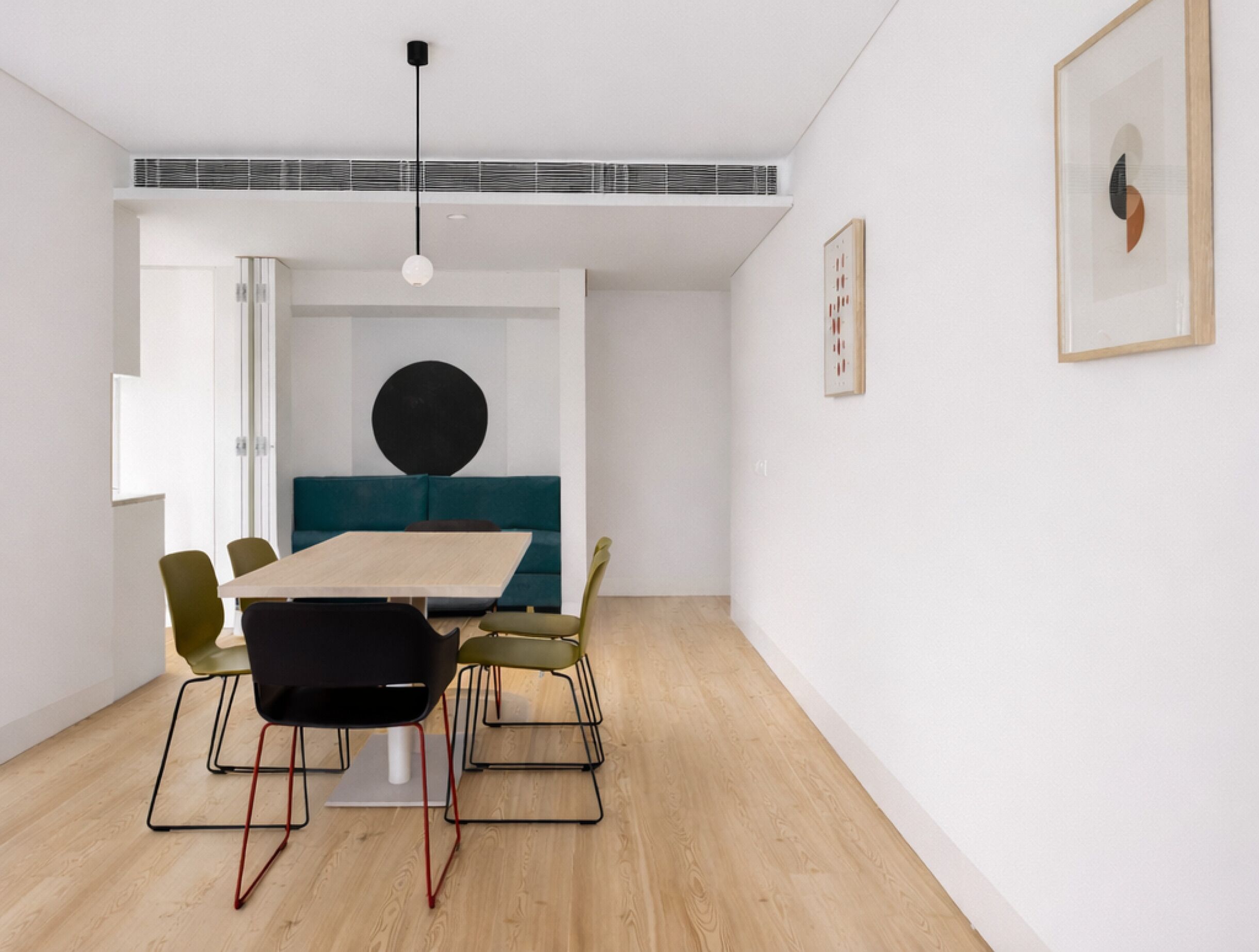 A modern dining area with a wooden table, chairs, and a blue sofa.