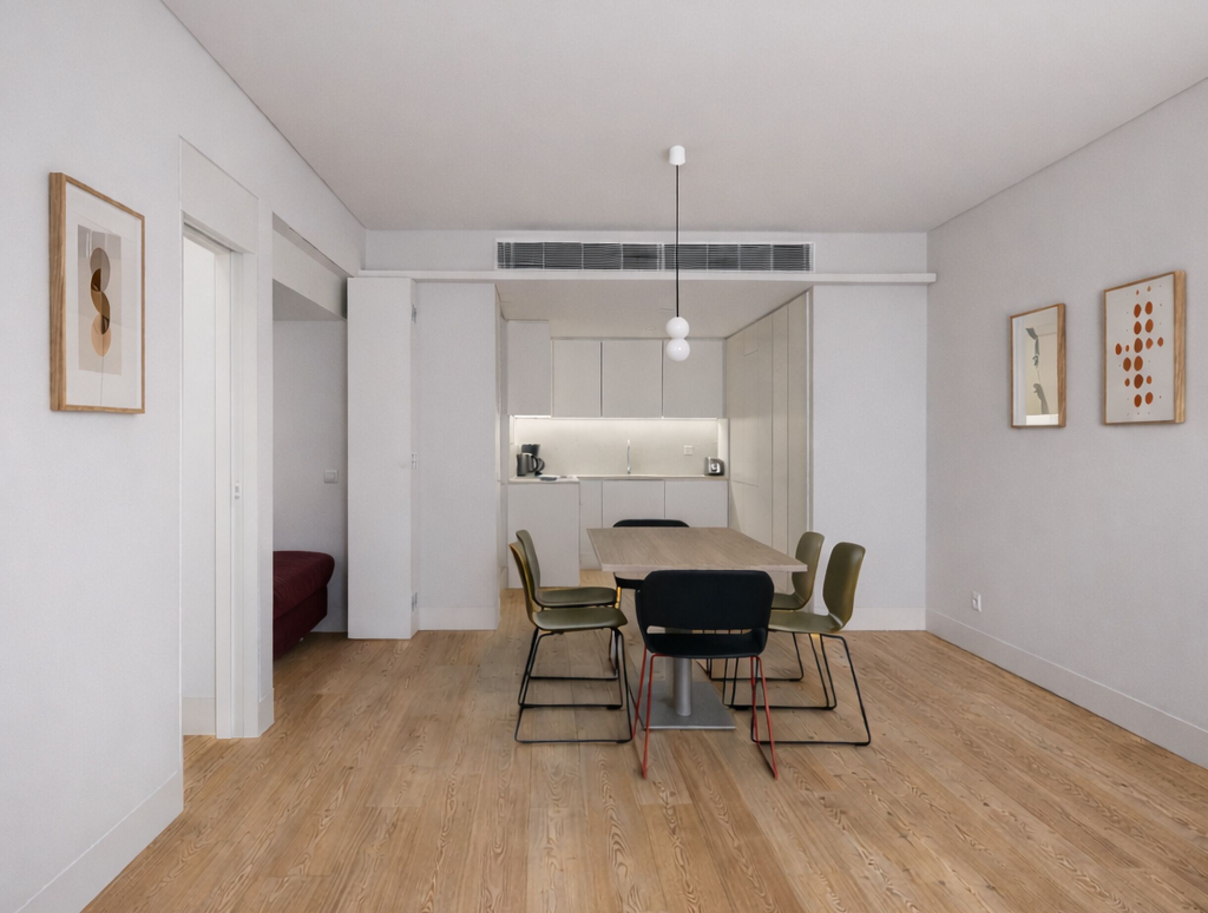 Un espace de salle à manger moderne avec une table en bois, des chaises et des luminaires suspendus.