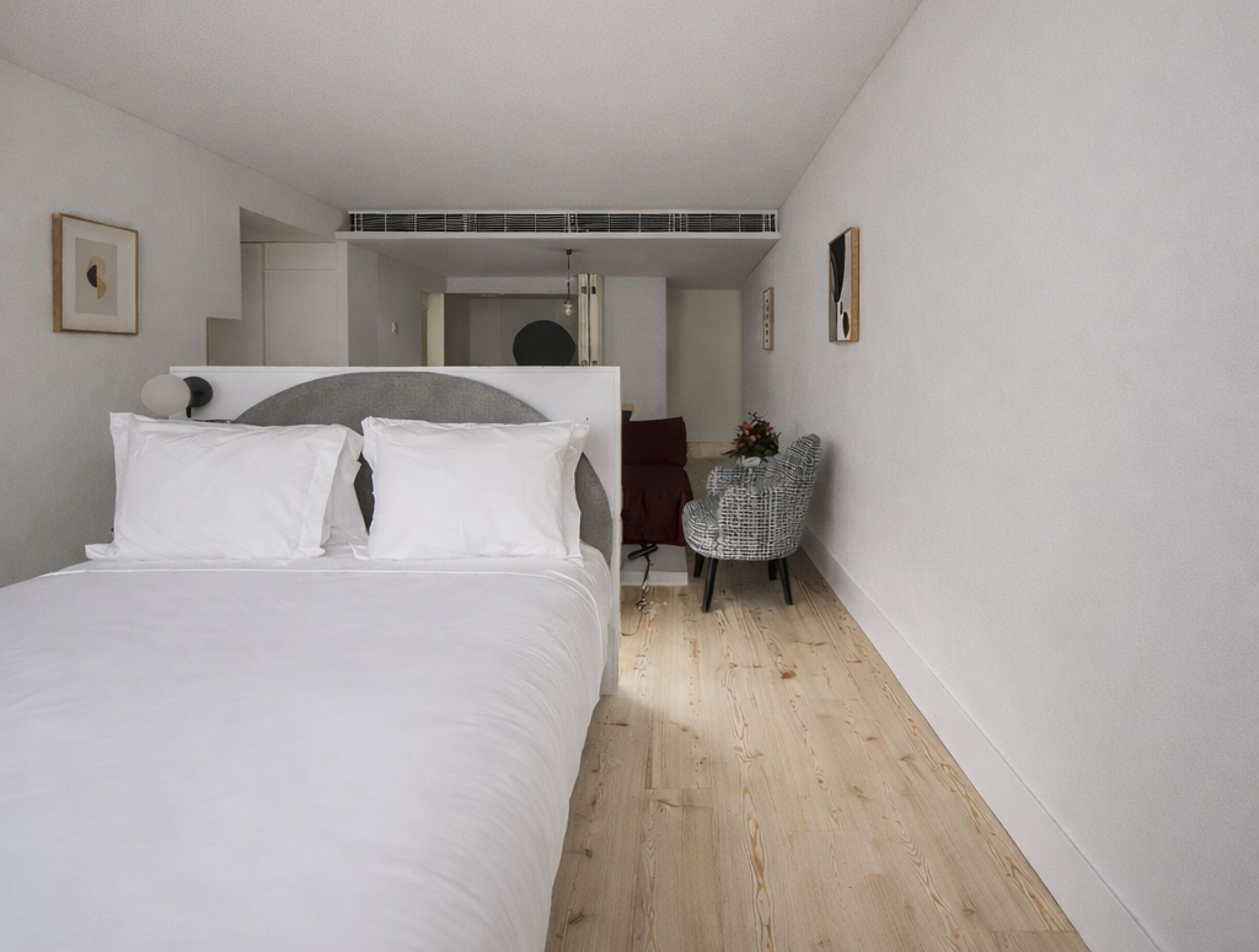 A bedroom with a bed, a chair, and a mirror.