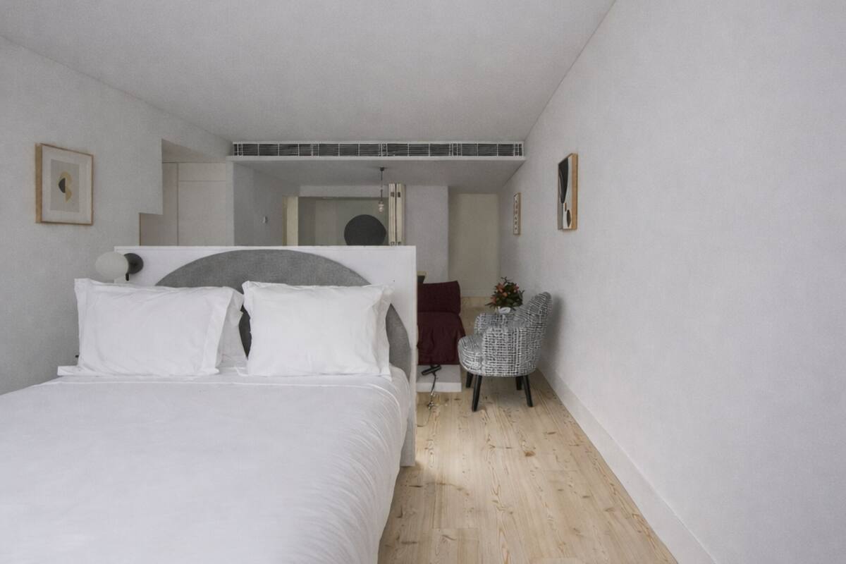 Un dormitorio con cama, una silla y un espejo.