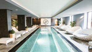 A swimming pool with lounge chairs and a logo on the wall.