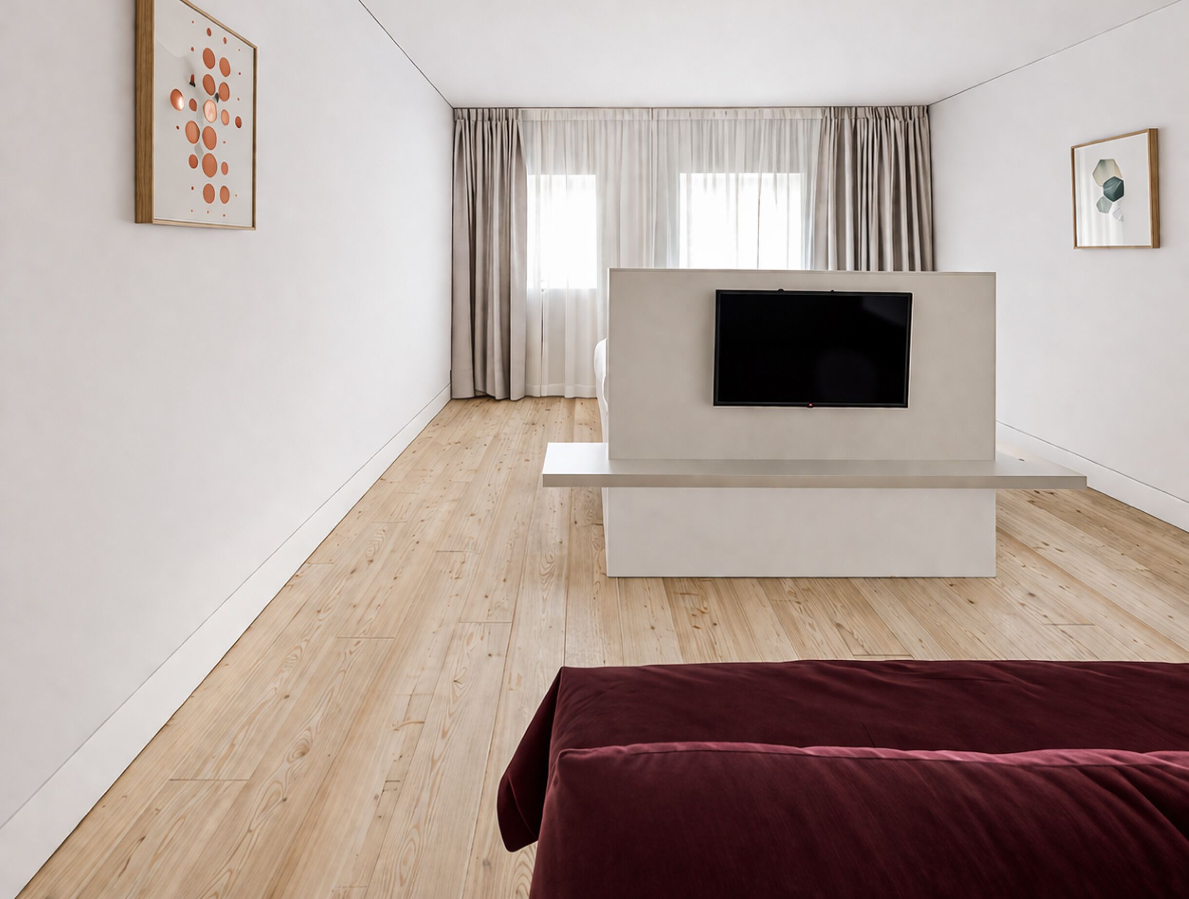 Una habitación moderna y minimalista con una televisión de pantalla plana sobre un soporte blanco, suelo de madera y un ventanal con cortinas.