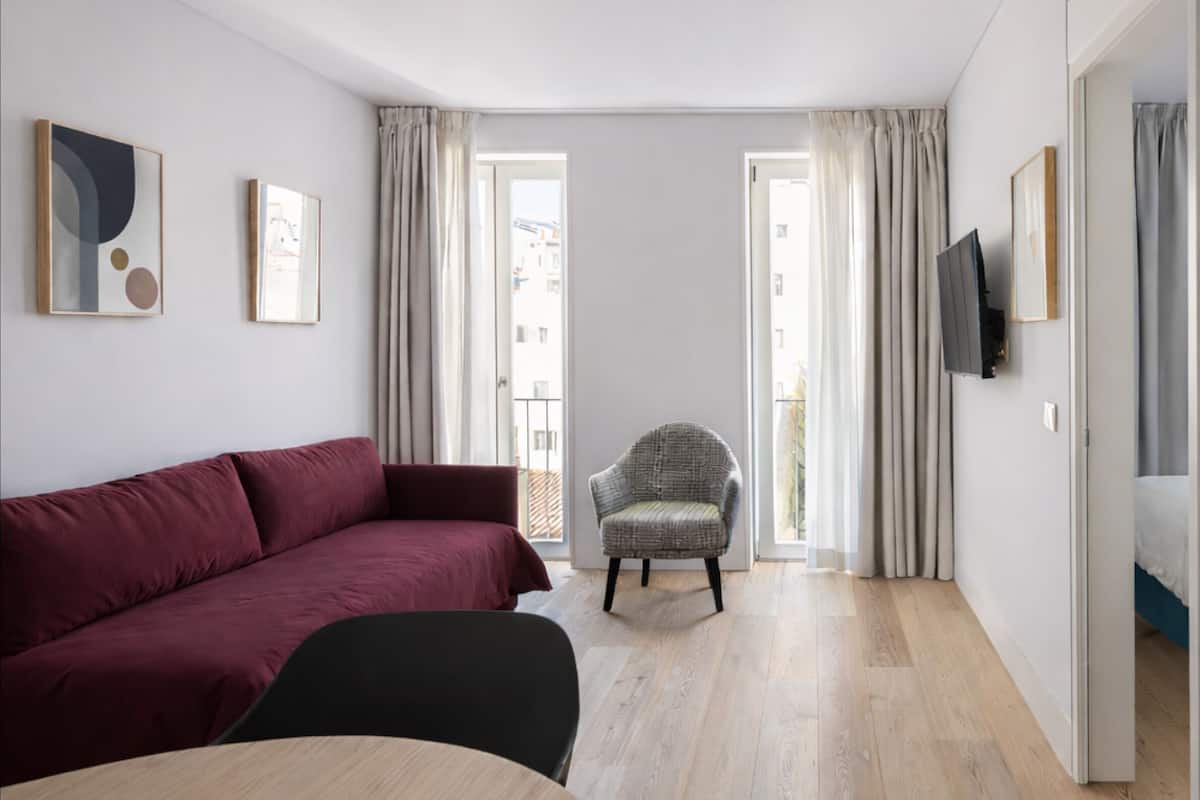 Una sala moderna con un sofá, un sillón y un televisor montado en la pared.