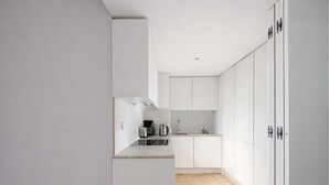 A modern kitchen with white cabinets, a wooden floor, and stainless steel appliances.