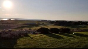Un paysage rural avec un plan d’eau, des collines douces et un ciel dégagé.