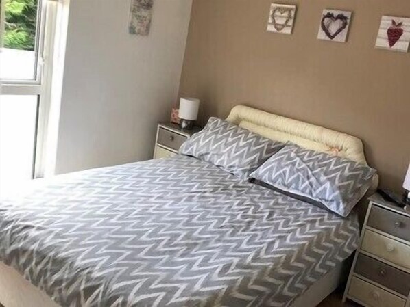 A bedroom with a bed, a nightstand, a lamp, and wall decorations.