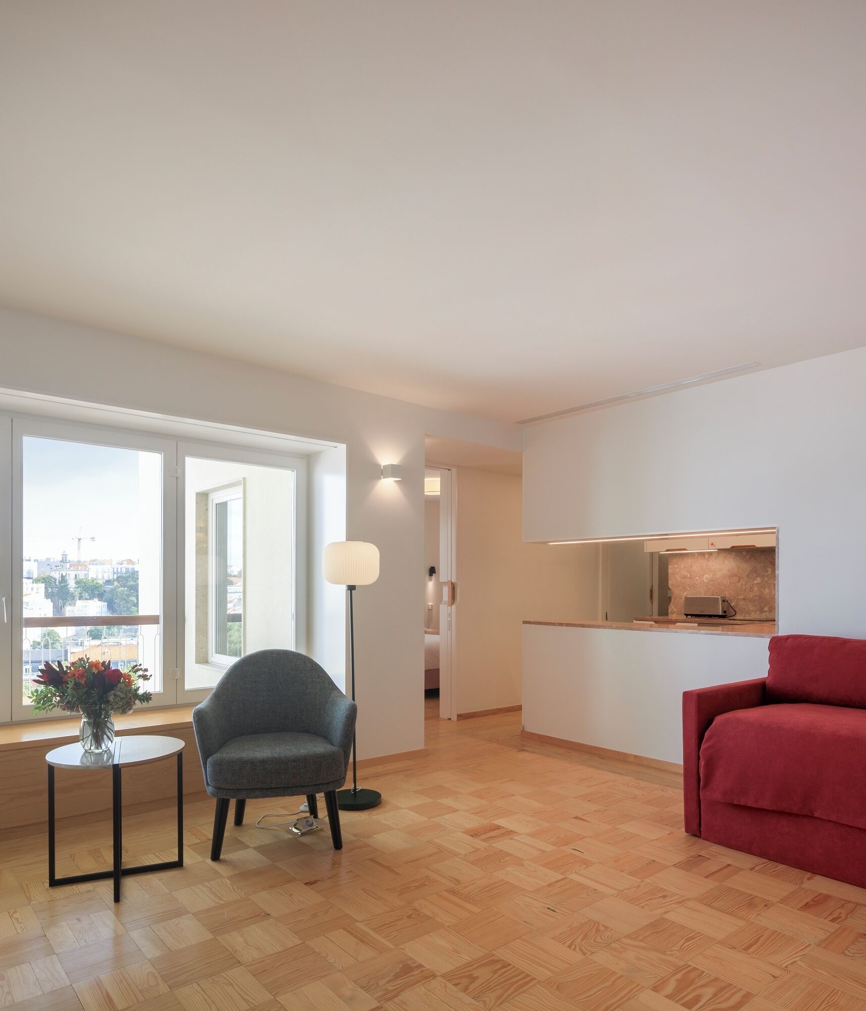 A modern living room with a sofa, a chair, a small table with a vase, and a floor lamp.
