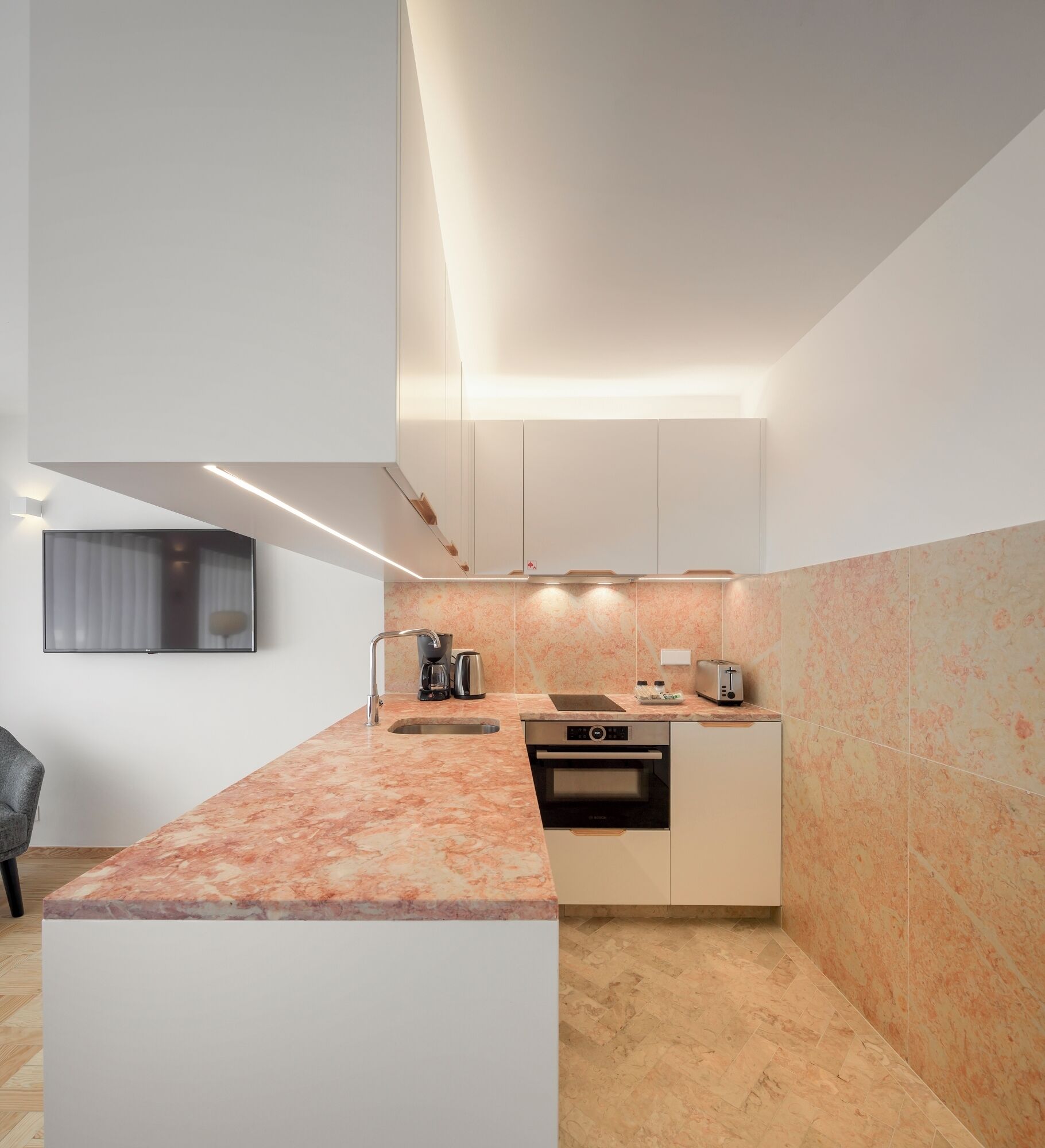 A modern kitchen with a marble countertop, built-in oven, and a large island.
