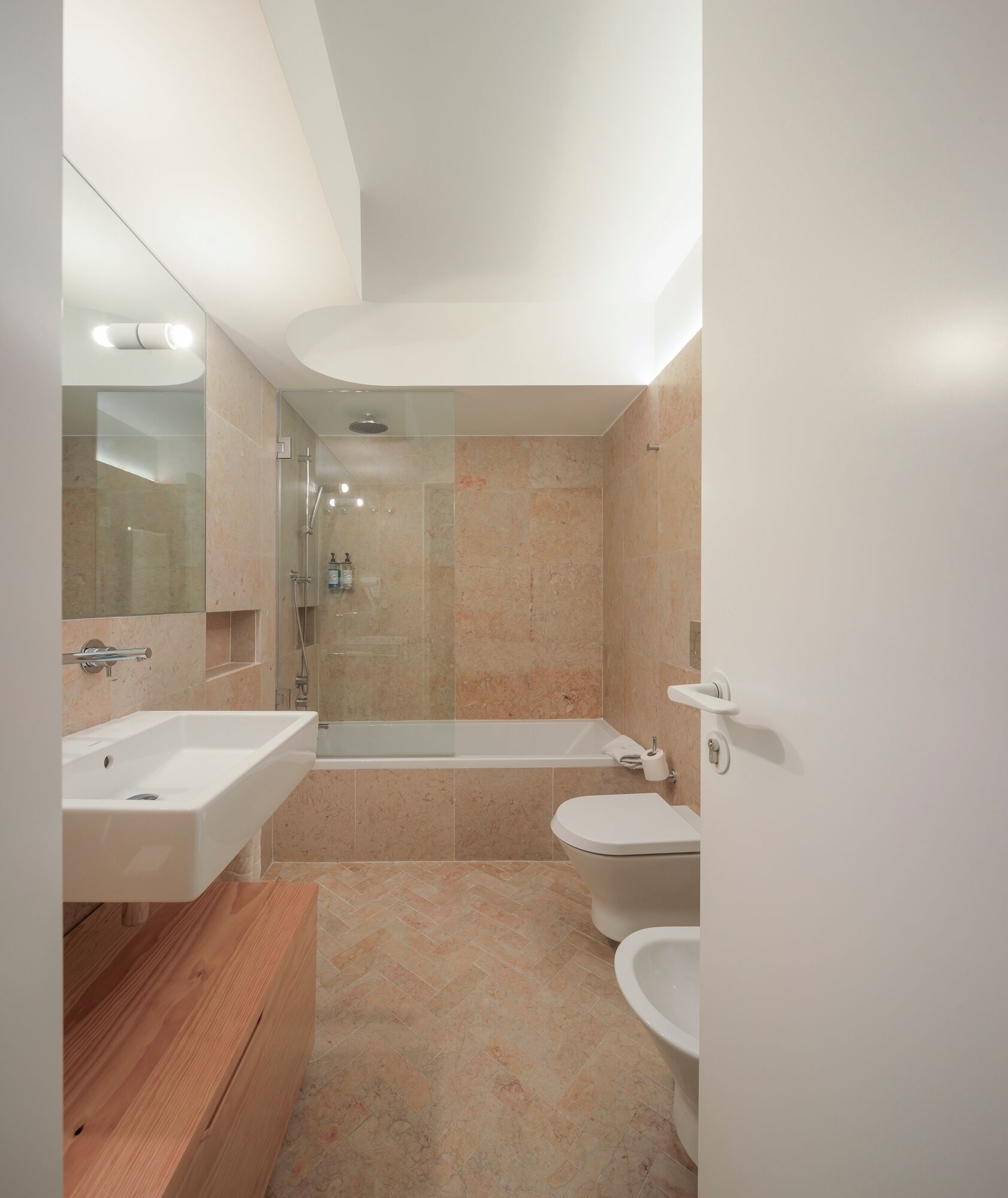 A modern bathroom with a shower, bathtub, and two sinks.