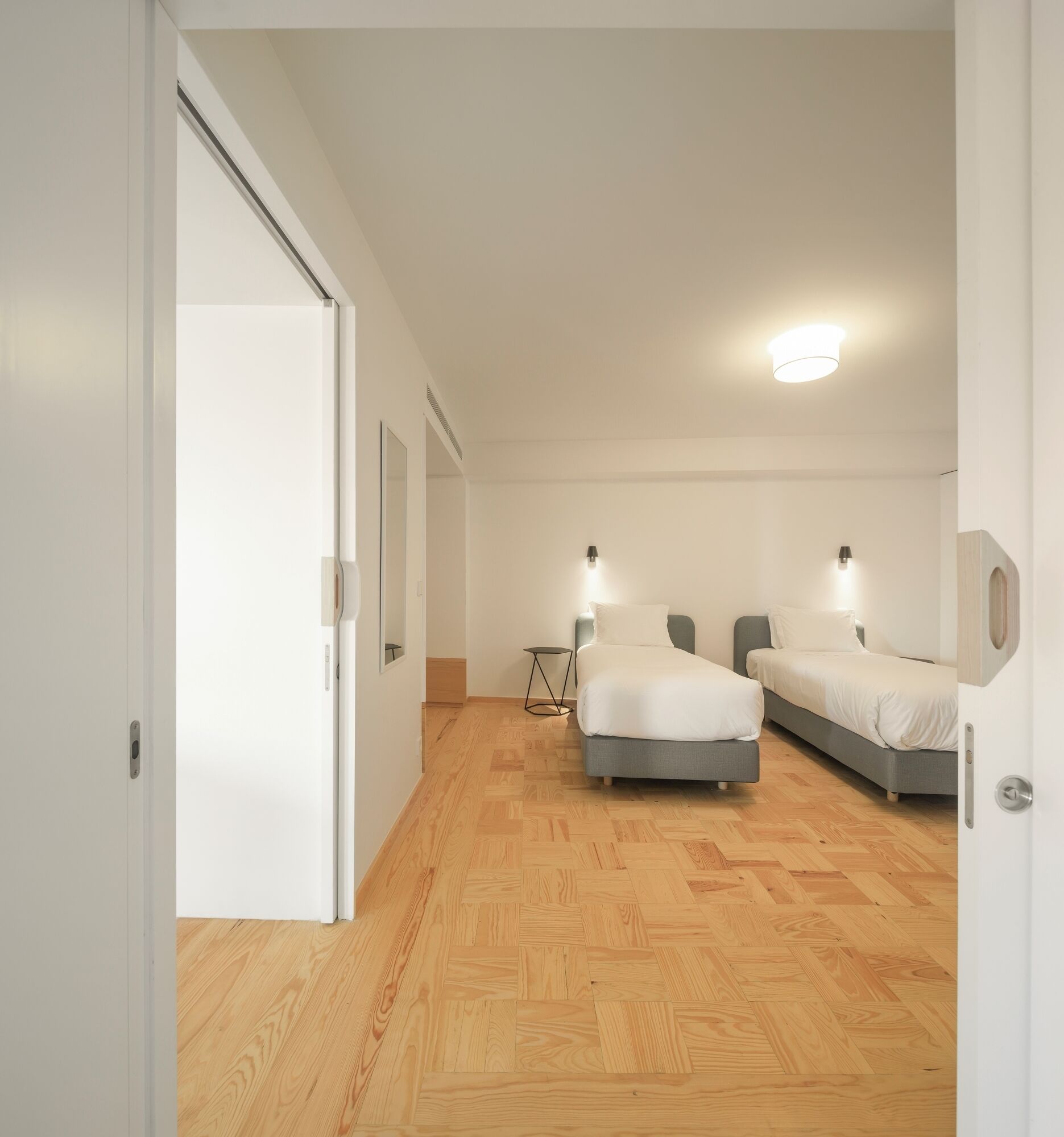 Ein Zimmer mit zwei Betten, einem kleinen Tisch und einem Spiegel.