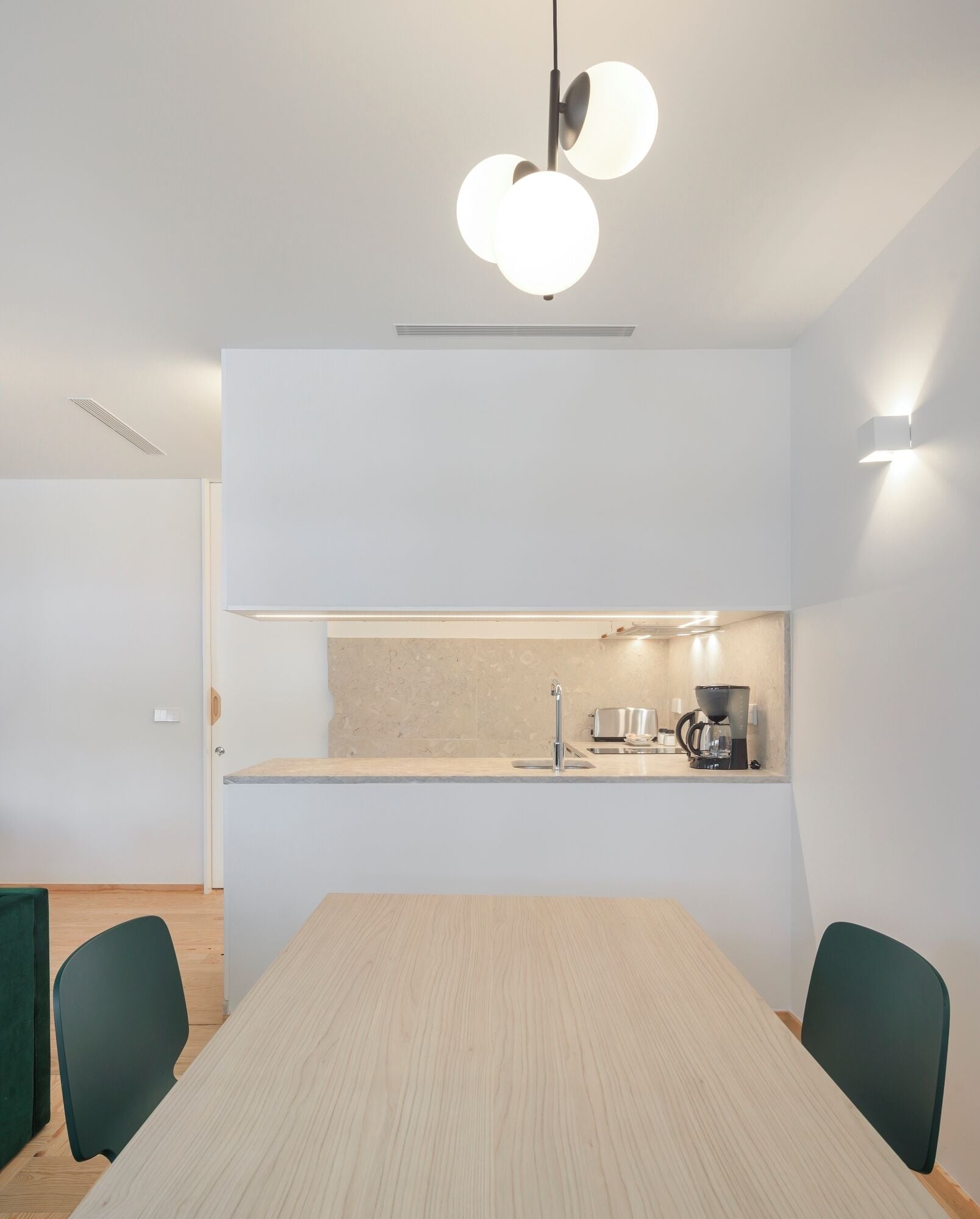 A modern kitchen with a built-in sink, a coffee machine, and a light fixture above the counter.