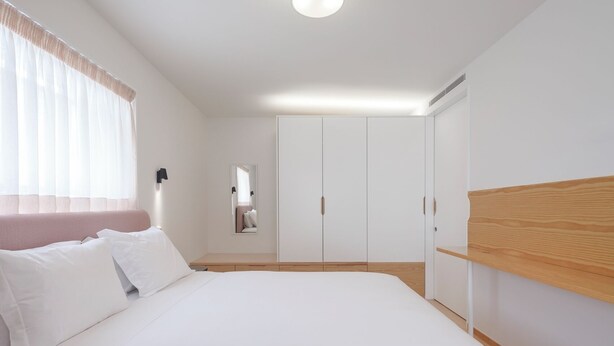 A bedroom with a bed, a wardrobe, and a mirror.