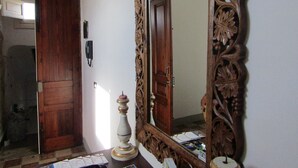 A room with a wooden door, a large ornate mirror, and a small table with a candle and cards.