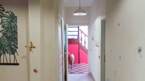 A hallway with a staircase leading to a red room.