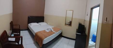 A small, single-bed room with a bed, a chair, a desk, a mirror, and a door.