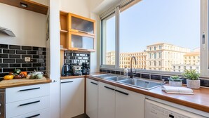 A modern kitchen with a large window, a dishwasher, and a countertop with various kitchen items. - La Belle Vue - 65m2 au dernier étage avec ascenseur (Marseille)