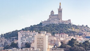 A historic building with a prominent tower on a hill, surrounded by residential buildings. - La Belle Vue - 65m2 au dernier étage avec ascenseur (Marseille)