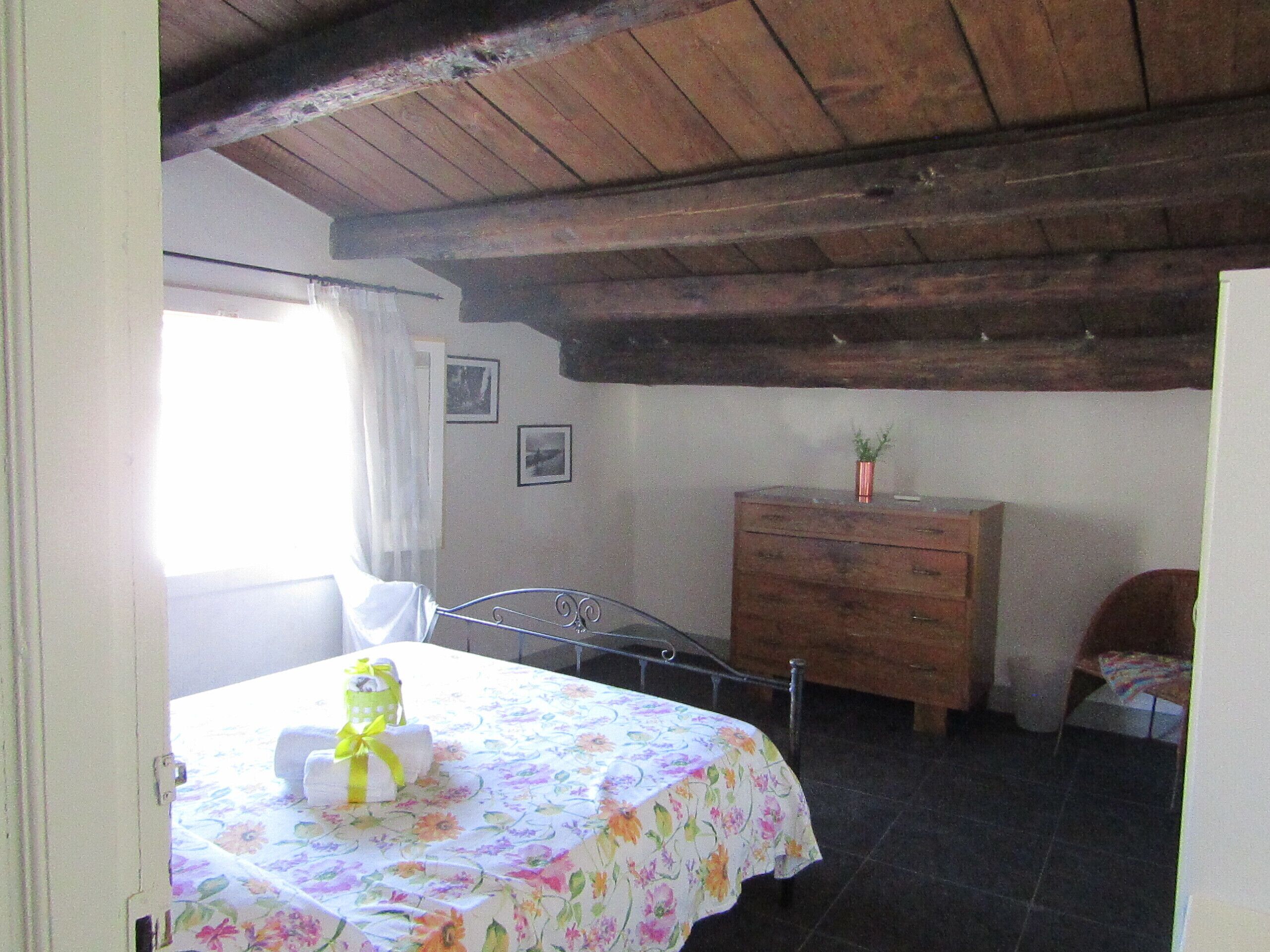 Une chambre à coucher avec un lit, une commode en bois et une fenêtre avec des rideaux.