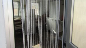 Une porte surmontée d’un rideau fait de fils blancs disposés verticalement.