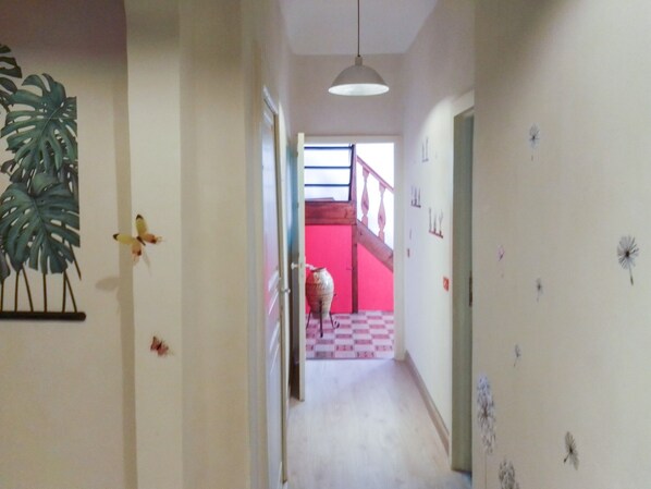 A hallway with a staircase leading to a red room.