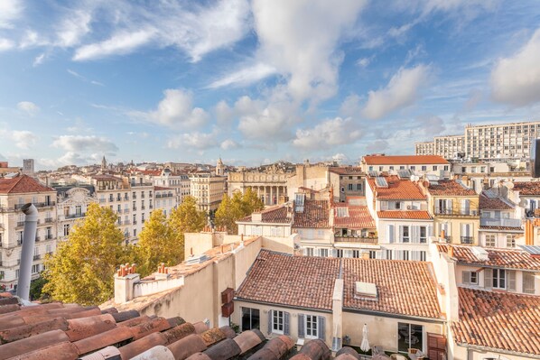 A cityscape with historic buildings, terracotta roofs, and a clear sky.