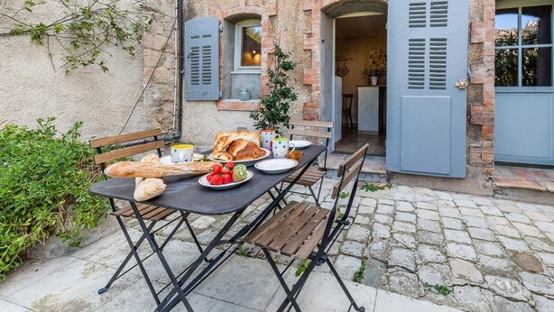 An outdoor dining area with a table set for breakfast, including bread, fruit, and cups. - La Petite Provence - Two Bedroom House, Sleeps 4 (Marseille)