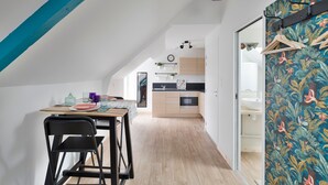 Une cuisine moderne avec des meubles en bois, un plan de travail noir et un luminaire suspendu.