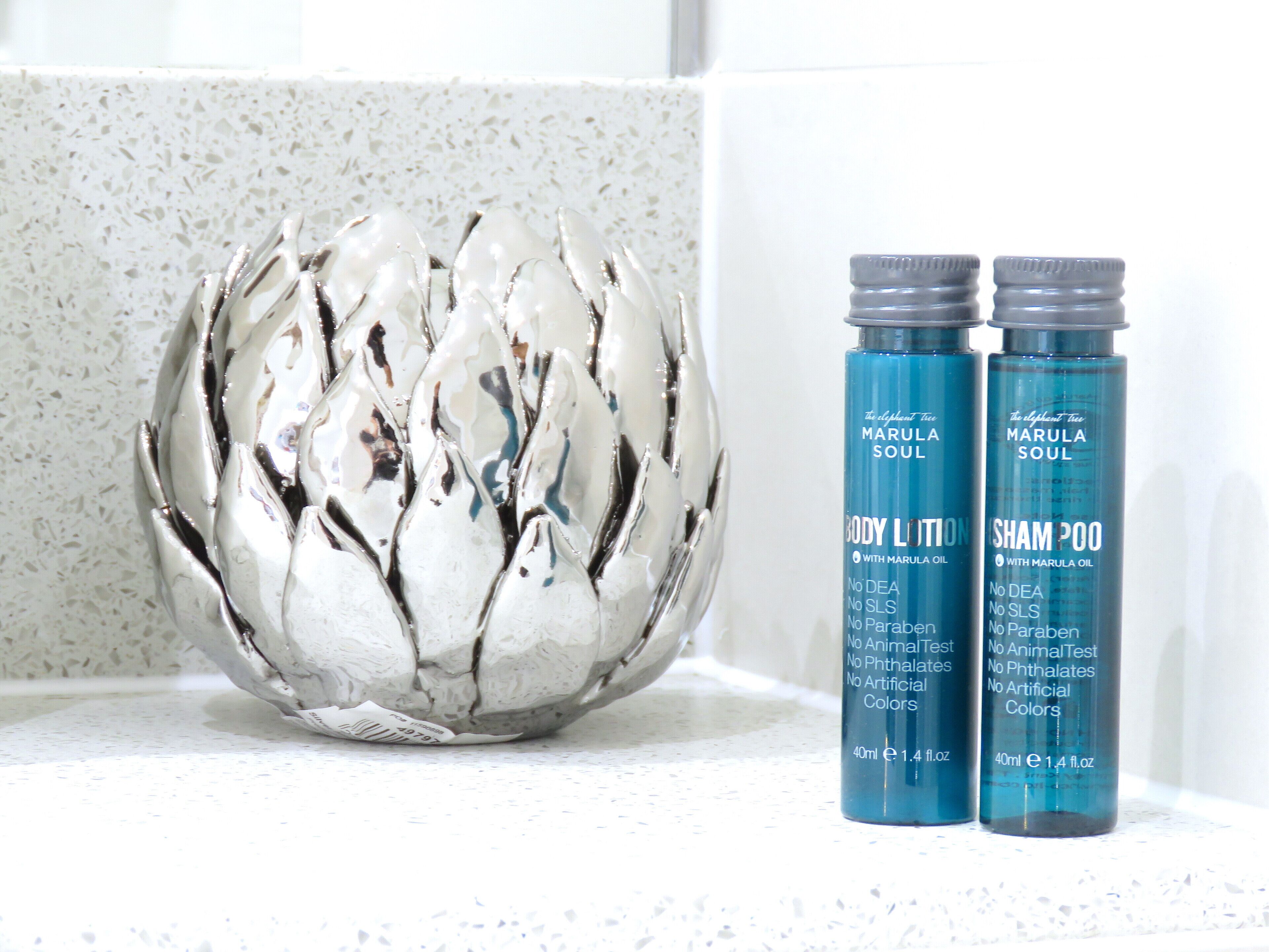 A decorative silver bowl and two bottles of Marula Soul body lotion and shampoo.